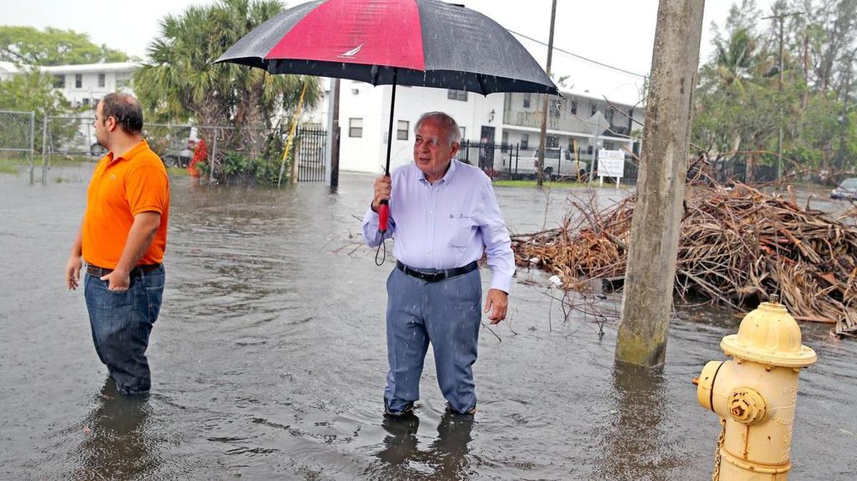 El alcalde de Miami, Tomás Regalado, y su hijo José, caminan por una calle inundada por la marea real en Shorecrest, en esta foto del 5 de octubre de 2017.