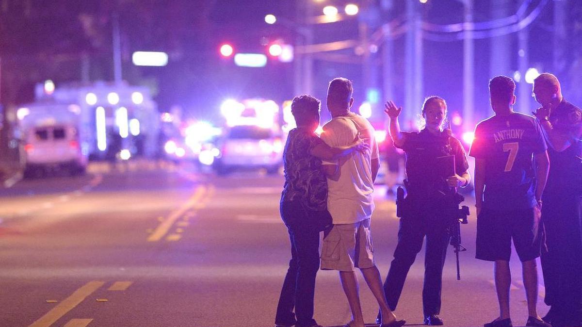 Agentes de policía de Orlando hablan con familiares en un tiroteo múltiple en un club nocturno en Orlando, Florida.