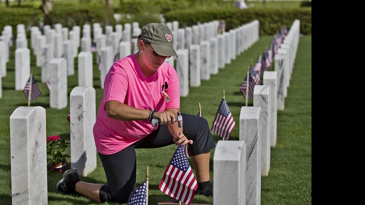 
Dara Ryan, de North Lauderhill, coloca banderas americanas en las tumbas de los veteranos en el Cementerio Nacional del Sur de la Florida, en Lake Worth, Palm Beach, este domingo.


