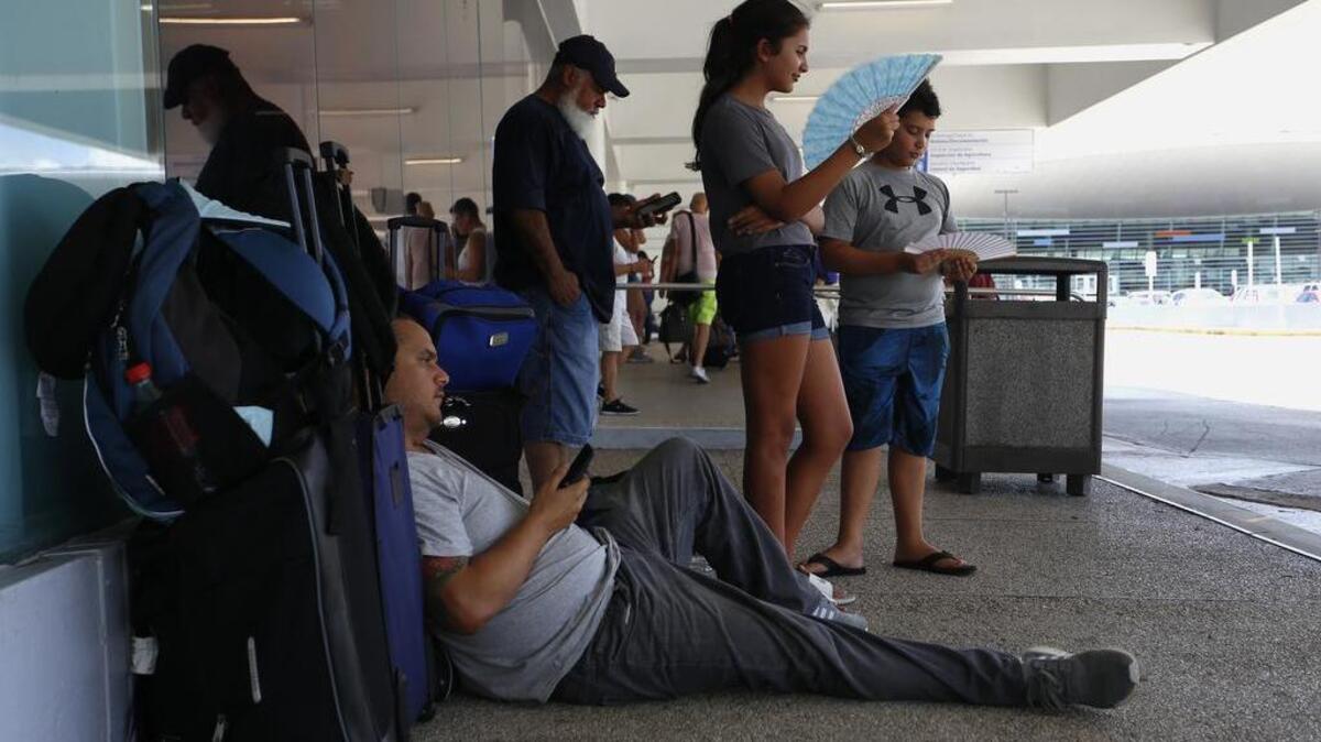 Pasajeros intentan obtener un vuelo el lunes, 25 de septiembre de 2017, en el Aeropuerto Internacional Luis Muñoz Marín en Carolina, Puerto Rico. Puertorriqueños llegaron a Miami en uno de los primeros vuelos que salieron de la isla tras el paso del huracán María para apaciguar la falta de electricidad, aire acondicionado y comunicaciones, e incluso para tratamientos médicos.