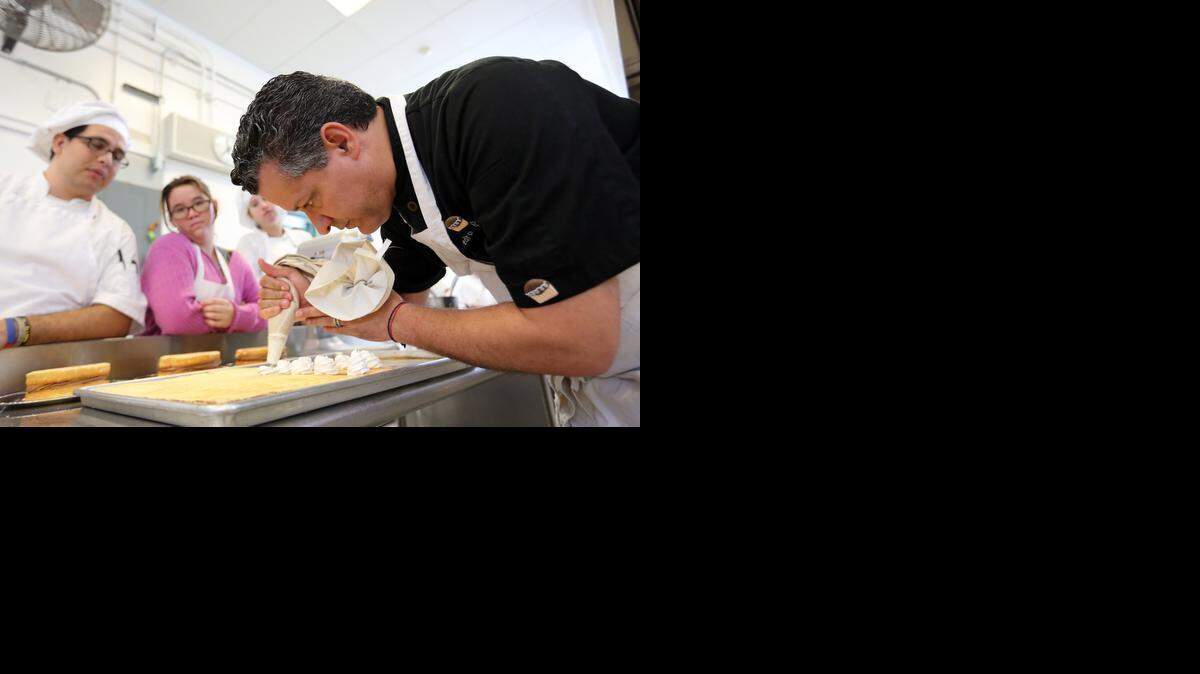 
El profesor Pedro Díaz muestra cómo se adorna con crema unas pequeñas tartas. Los estudiantes Camilo Nunez, Sophia Cruz, y Angela Lombardo lo miran con atención, el miércoles.


