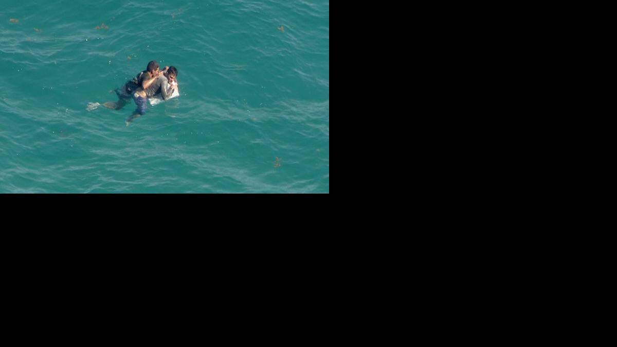 
Dos hombres se aferran a los restos de una embarcación el lunes en la Bahía de Biscayne antes de ser rescatados.
