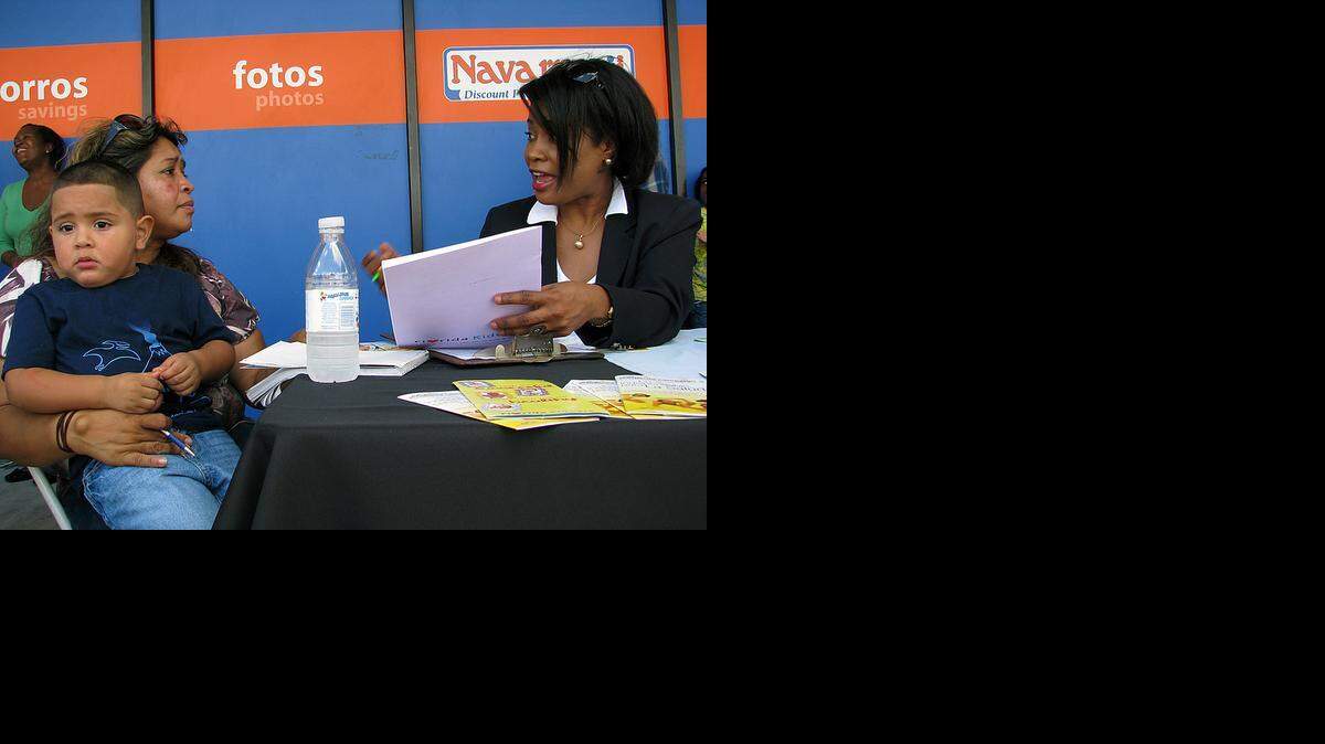 
Reina Lobo carga a su nieto, Julio, mietras escucha la información que le da Nadine Gousse sobre cómo inscibirlo en KidCare, en esta foto de archivo.
