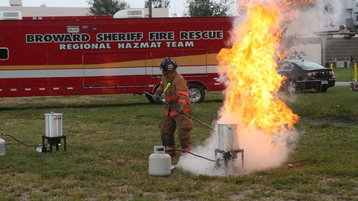 El bombero Nick Maggio coloca un pavo congelado en una cazuela de aceite hirviendo, en una demostración en la Academia de Bomberos de Broward, para ilustrar los peligros de ese tipo de preparación de pavos.