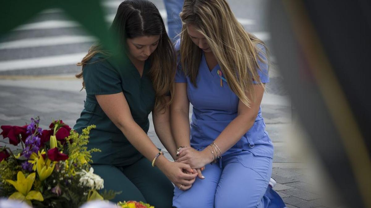 Unas mujeres oran junto a cruces en un memorial en tributo a las víctimas del tiroteo de Orlando, el jueves 16 de junio de 2016, cerca la Centro Médico Orlando Regional, de Orlando, Florida (EEUU).