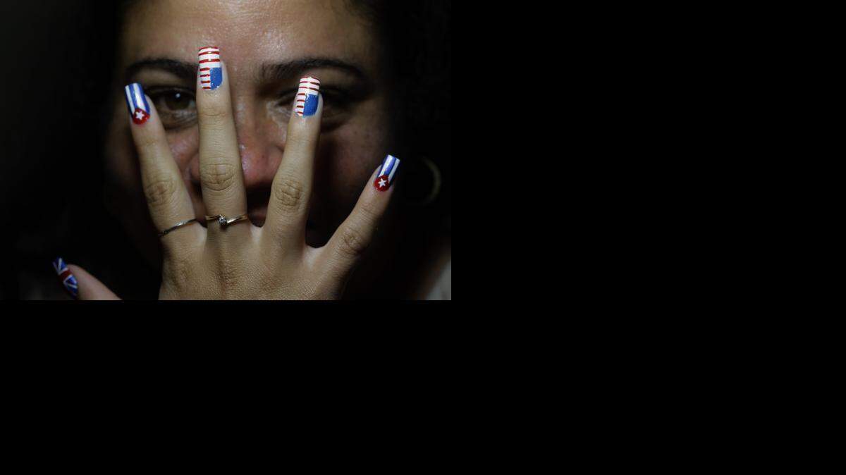 
Marilyn Alvarez posa para una fotografía con la mano de una de sus clientas, con las uñas acabadas de pintar, en su casa de La Habana el 22 de diciembre.
