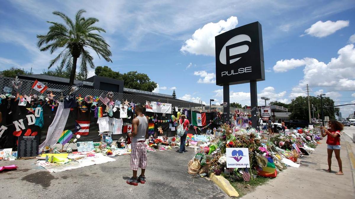 Visitantes se toman fotos y colocan artículos en un monumento improvisado fuera del club nocturno Pulse, el 11 de julio de 2016, en Orlando, Florida.