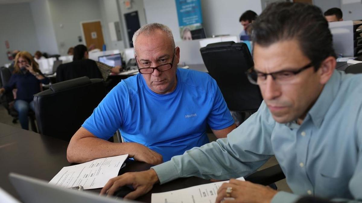 Alberto Abin (der), consejero de seguros para UniVista Insurance, ayuda a Carlos Rodríguez a decidirse por un plan como parte del Affordable Care Act (Obamacare), en Miami.