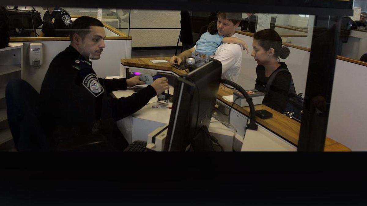 Un funcionario de control de pasaportes en el Aeropuerto Internacional de Miami procesa a viajeros internacionales.