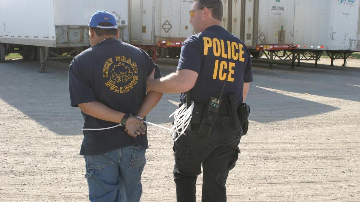 An immigration agent with a detained man.

