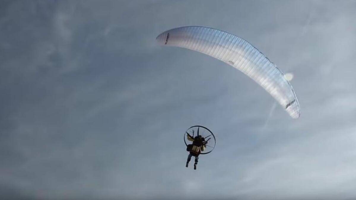Los aficionados al paramotor vuelvan en una aeronave compuesta de un pequeño motor de hélice y un parapente.