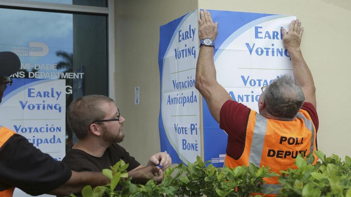 Empleados del Departamento de Elecciones de Miami Dade colocan carteles al inicio de la votación anticipada para las elecciones presidenciales del 8 de noviembre.