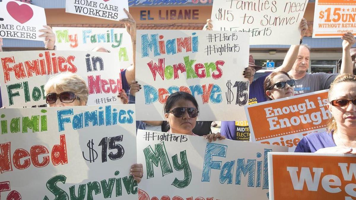 
Un grupo de manifestantes en Miami sostiene carteles alusivos al alza del salario mínimo el lunes.

