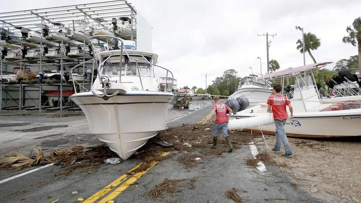 Personas caminan ebntre escombros y barcos en la carretera después que el huracán Hermine pasó por la zona el viernes 2 de septiembre de 2016 en Steinhatchee, Florida.