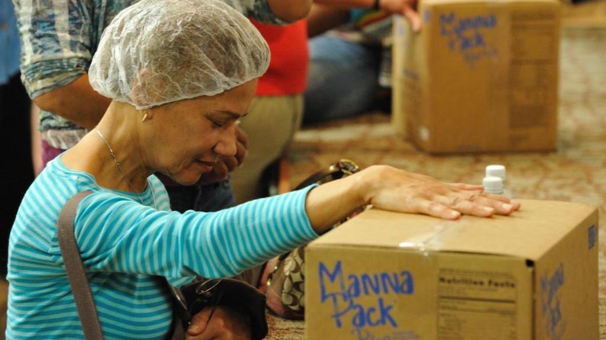En un evento pasado de Feed My Starving Children una de las participantes ora por los niños que recibirán las comidas.