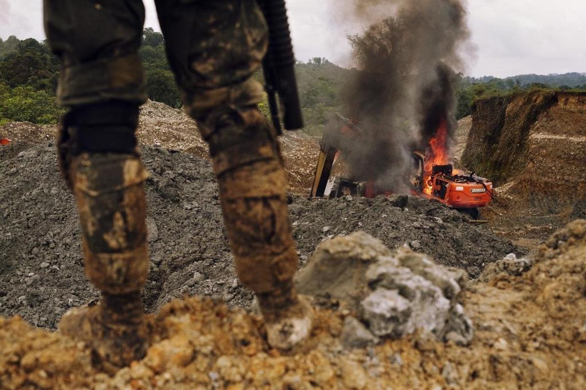 Un policía hace guardia en el suroeste de Colombia después que las autoridades destruyeron excavadoras que se usaban para operaciones ilegales de minería.