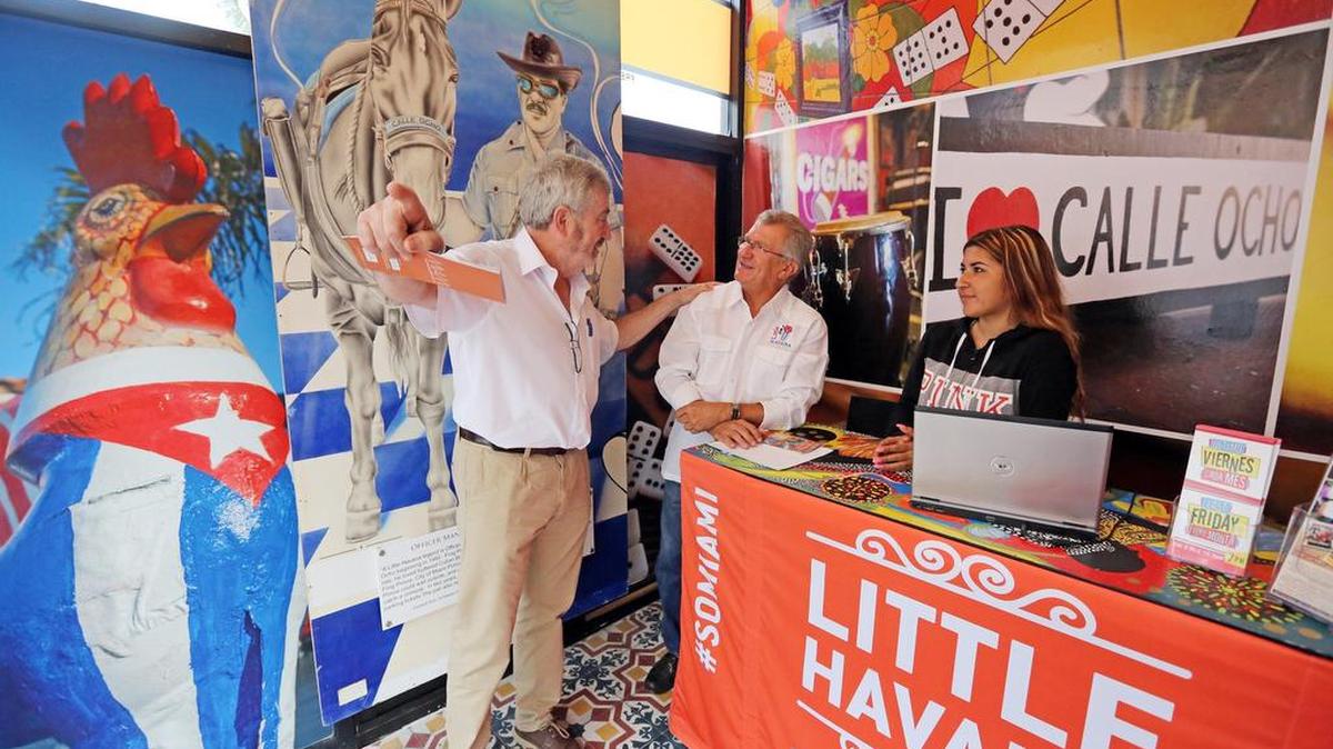 El turista español Antonio Martín del Río (izq.), habla con Miguel Ramos y Lara Vázquez en un local de La Pequeña Habana.