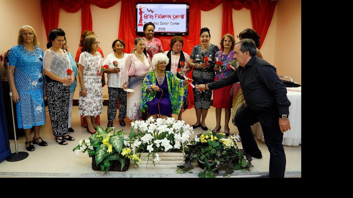
Vincent Delgado (izq.) le entrega a Lola Harvey unas flores y un certificado después del Show de Modas para la Tercera Edad en De Hostos Senior Center en Hialeah.

