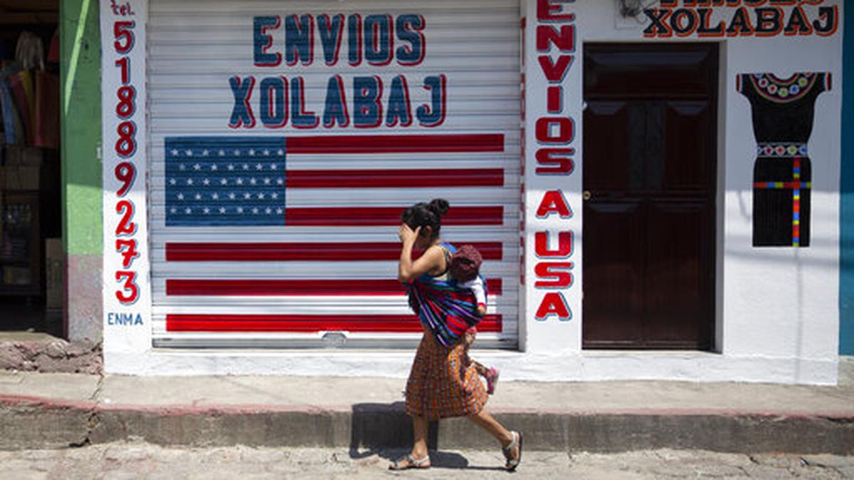 El 3 de abril de 2020 una mujer pasa frente a un negocio de mensajería y envío de dinero en el pueblo mayoritariamente indígena de Joyabaj, Guatemala. El país centroamericano está entre los primeros diez de Latinoamérica y el Caribe que más remesas recibieron en 2021.