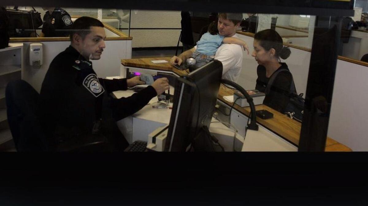 Esta del 19 de enero del 2007 muestra a un funcionario de control de pasaportes en el Aeropuerto Internacional de Miami atendiendo a pasajeros internacionales.