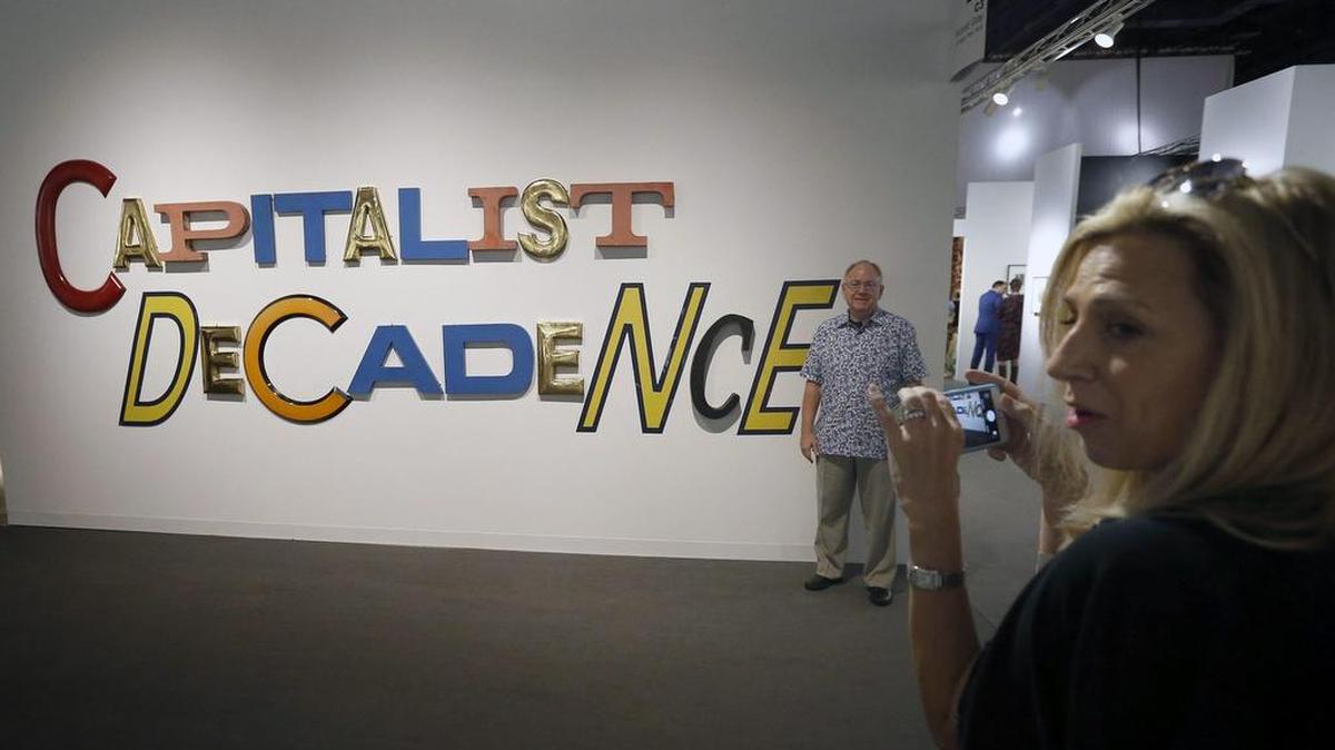 Una mujer hace una fotografía de la obra 'Decadencia Capitalista' del artista estadounidense Jack Pierson durante el festival Art Basel de Miami, Estados Unidos, el 30 de noviembre de 2016. Art Basel concentra al menos 250 obras de arte en el centro cultural Miami Beach.