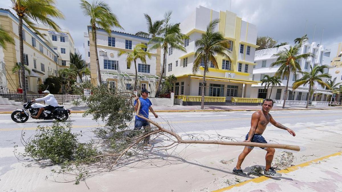 Dos hombres retiran un árbol frente un hotel el lunes 11 de septiembre de 2017, luego del paso del huracán Irma en Miami Beach, Florida, en donde aún hay zonas que no tienen electricidad.
