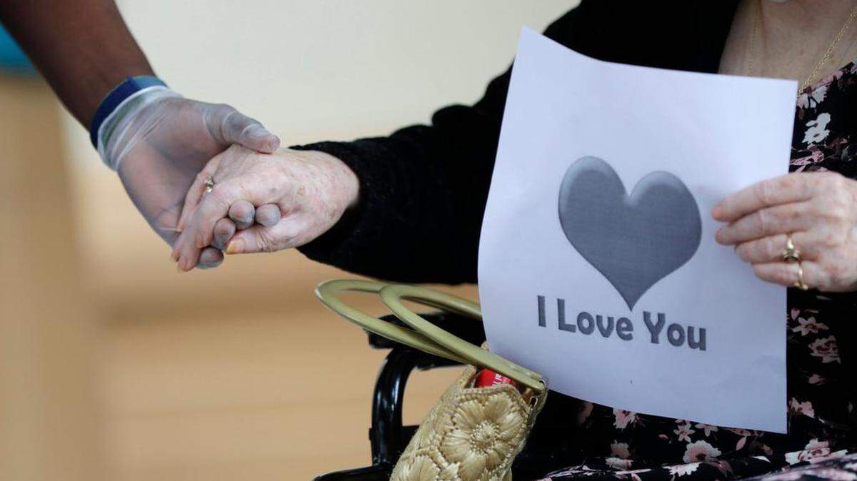 A senior citizen holds the hand of a care coordinator at a health facility in Miami in this photo from July 17, 2020.