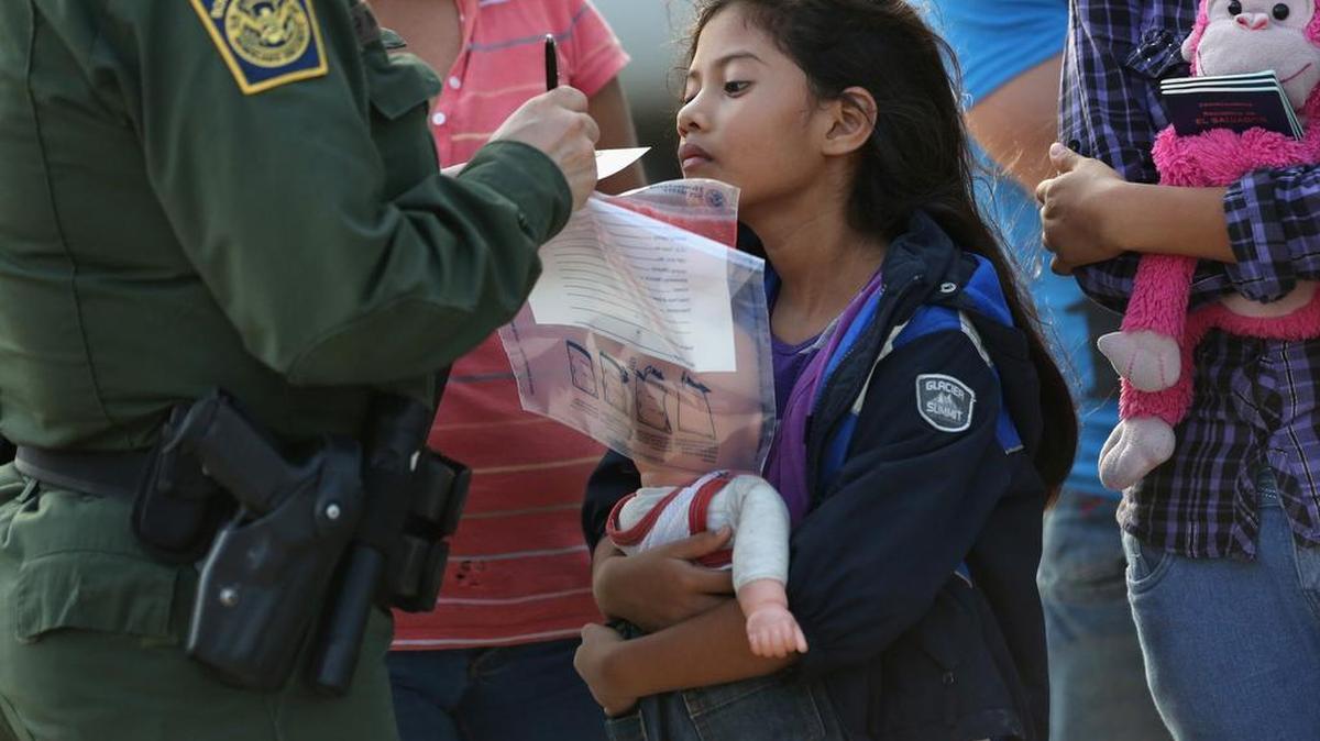 
La menor salvadoreña, Stefany Marjorie, de 8 años, observa como un agente de la Patrulla Fronteriza de Estados Unidos escribe datos de su familia, el 24 de julio del 2014 en de Mission, Texas.

