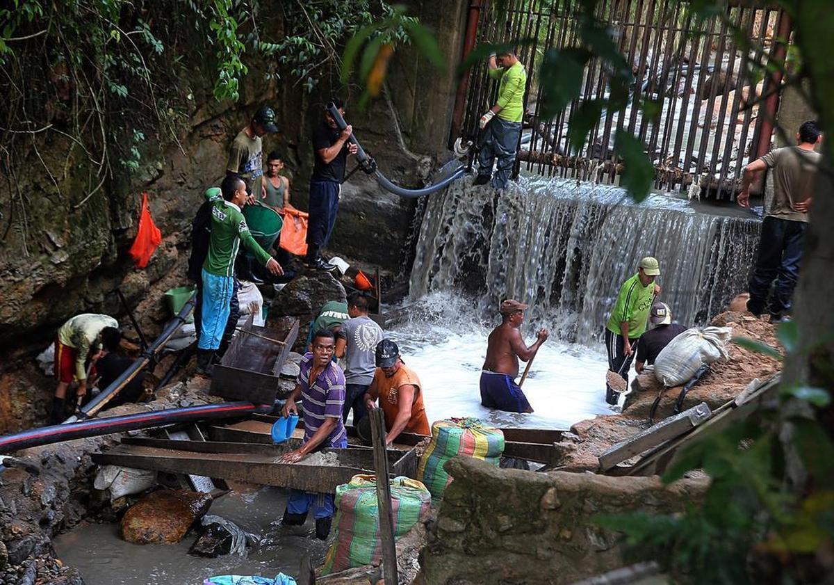 Un grupo de personas, entre ellas mujeres y niños, buscan oro en la arena fina del agua que echan a un río llamado Cianurada, después de procesarla en la fábrica de Gran Colombia Gold Corporation, en el poblado minero de Segovia, departamento de Antioquia, Colombia.