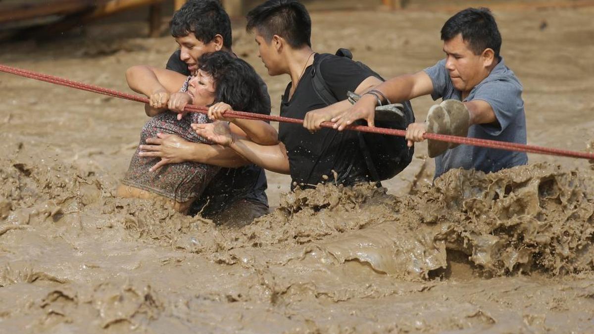 Varias personas intentan cruzar en marzo pasado una zona inundada en Perú. Las intensas lluvias han dejado al menos 106 personas muertas, casi un millón de afectados y 210,000 viviendas dañadas.