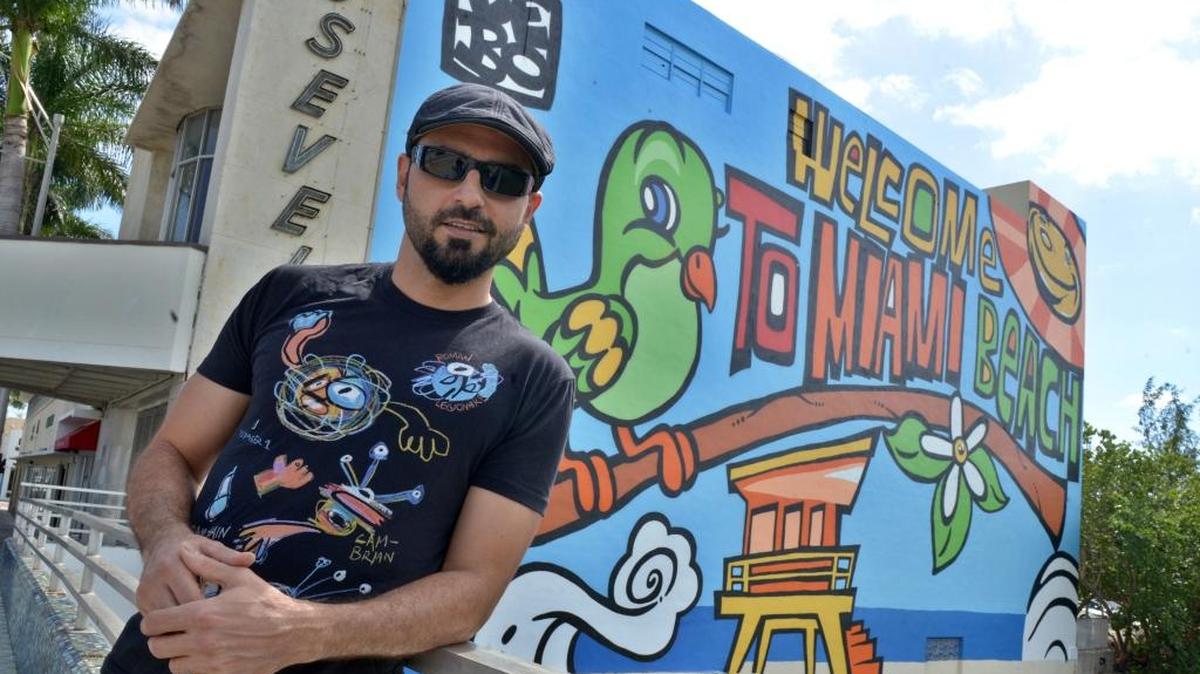 El artista de origen cubano Lebo posa frente a su mural "Welcome to Miami Beach" pintado en las paredes del abandonado teatro Roosevelt y que está pensado para servir como un punto de referencia para la población local, turistas y amantes del arte de todo el mundo.