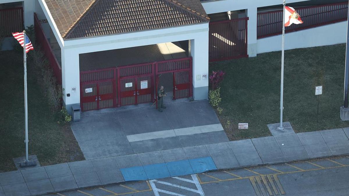 Un policía hace guardia en la puerta principal de la secundaria Marjory Stoneman Douglas en Parkland, Broward, donde 17 personas murieron baleadas el miércoles.