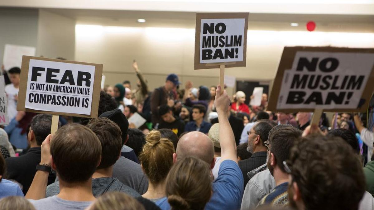 Decenas de personas protestan contra la orden ejecutiva del presidente Donald Trump que prohíbe la entrada a ciertos inmigrantes de varios países musulmanes, el domingo en el Aeropuerto Internacional de Dallas-Fort Worth, Texas.