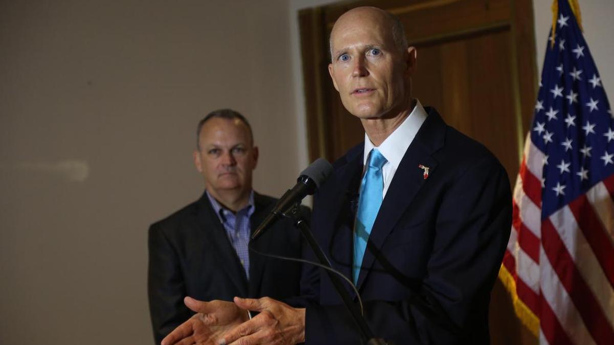 El gobernador de Florida Rick Scott (cen) en una conferencia de prensa con el presidente de la Cámara de Representantes estatal, Richard Corcoran, en el Aeropuerto Internacional de Miami el 2 de junio de 2017.