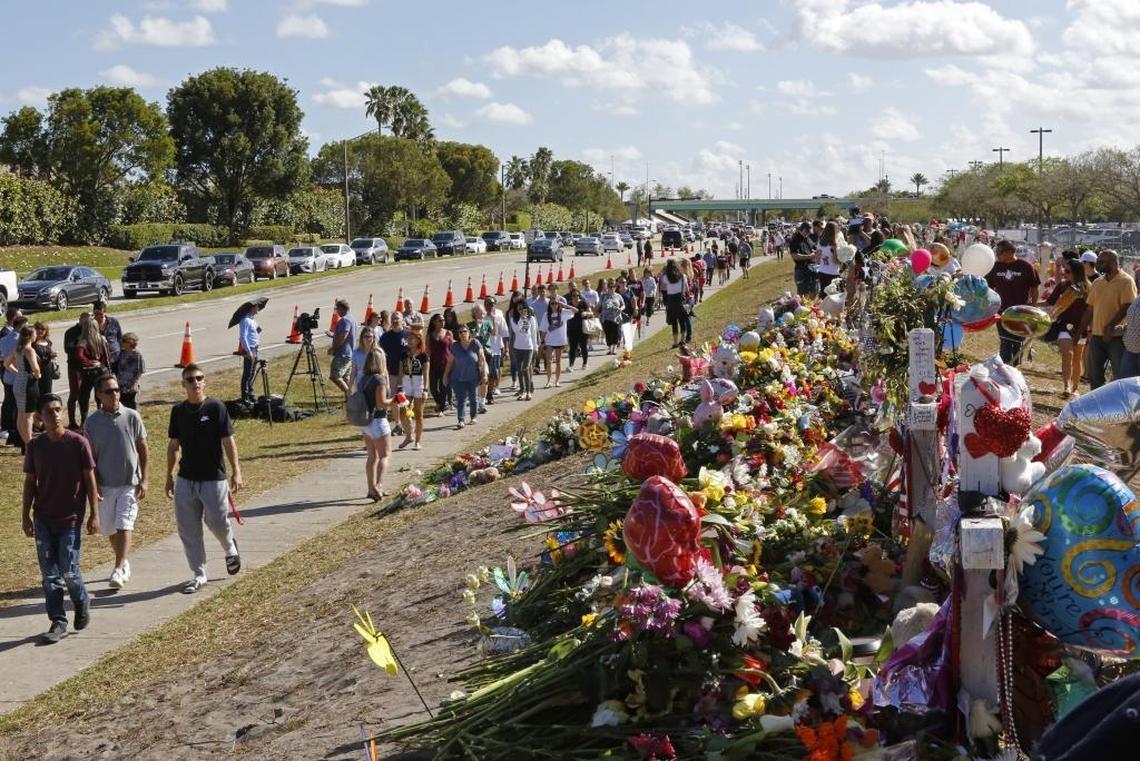 Padres y estudiantes caminan el 25 de febrero junto a un memorial cerca de la secundaria Marjory Stoneman Douglas en honor a las víctimas de la masacre del Día de San Valentín.