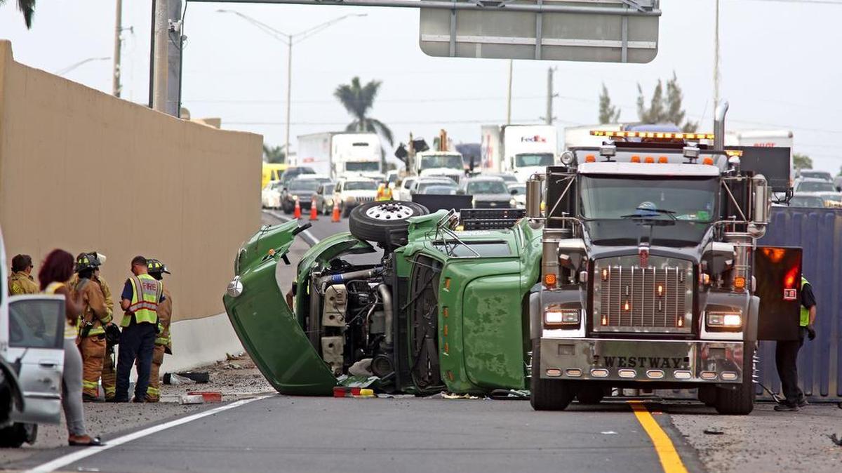 Paramédicos, personal de rescate y un camión de remolque trabajan en la escena de un accidente donde una rastra chocó con dos vehículos y luego se volcó, en la I-95 a la altura de Sheridan Street, en el Condado Broward.