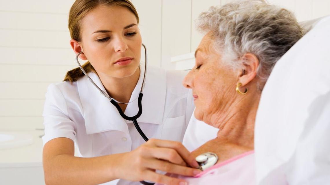 Una enfermera monitorea los latidos del corazón de una mujer de la tercera edad.