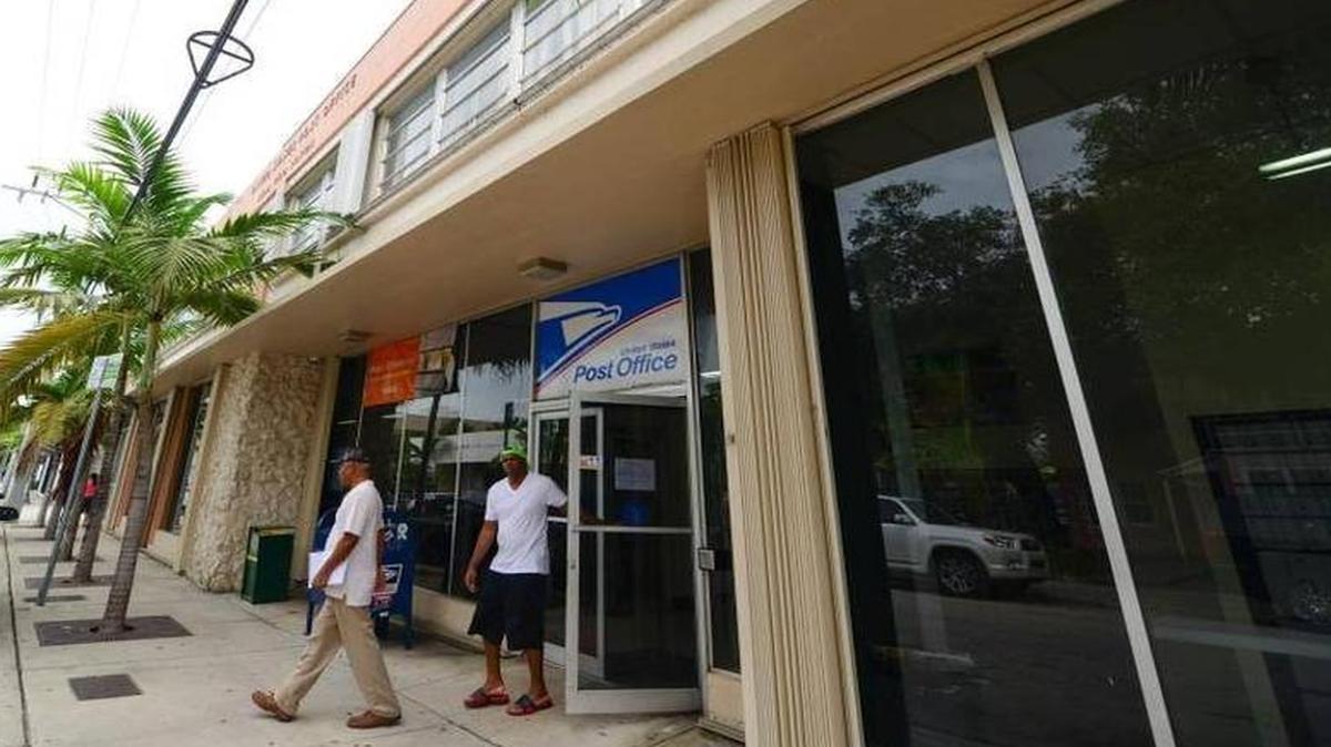 Los residentes de Miami, Randy Trey, 57 y Tayvion Smart, 32, salen de la oficina de correos en 66 NE 39th Street en el Design District de Miami el viernes, 18 de diciembre.