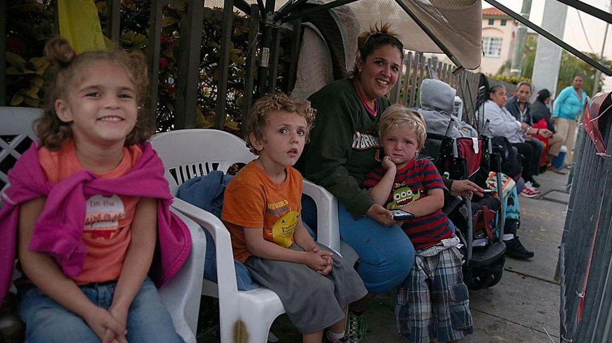 Ivette García y sus hijos (de izq. a der.) María, Daniel, Enrique, han estado en la fila esperando recibir alimentos gratis, durante el evento anual de la Camacol que distribuye alimentos durante los feriados del fin de año. Foto de archivo.