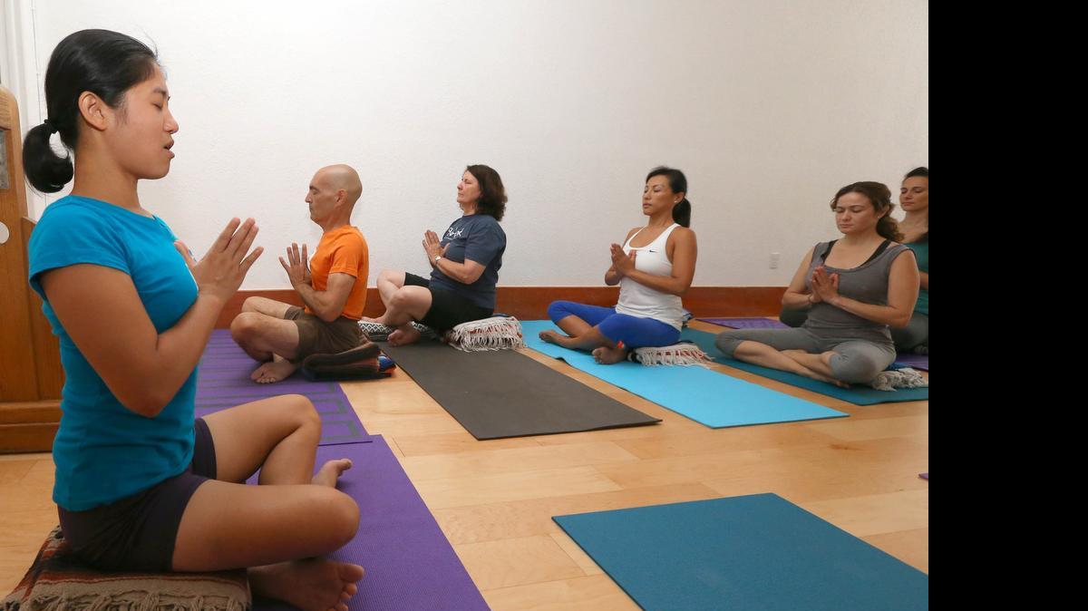 
Los instructores de yoga Pom (izq.) y Enrique Cayeiro (camiseta naranja), durante una clase en el Iyengar Yoga Center en Miami Beach.
