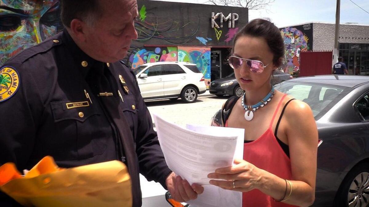 Un agente de la Policía de Miami entrega información sobre los riesgos del zika a una turista que paseaba el miércoles por la mañana por el área de Wynwood.