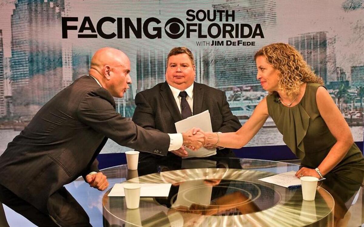 Los candidatos al Congreso de EEUU, Tim Canova (izq.) y Debbie Wasserman Schultz se dan un apretón de manos antes de proceder al debate con el moderador Jim DeFede.