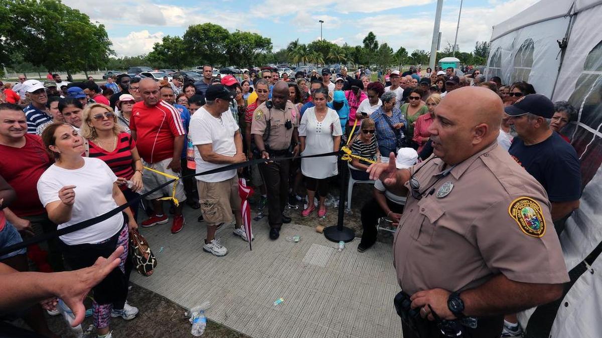 Un oficial de policía se dirige a un grupo de personas que esperan en línea en el centro de asistencia alimentaria de FEMA en Amelia Earhart Park en Hialeah el sábado 14 de octubre de 2017. 