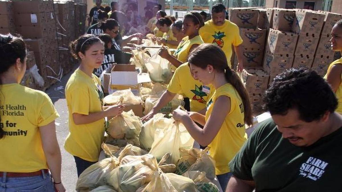 
Voluntarios ayudan a llenar bolsas con vegetales en un evento especial de distribución de comida Farm Share en Sweetwater, el 15 de junio de 2013. 
