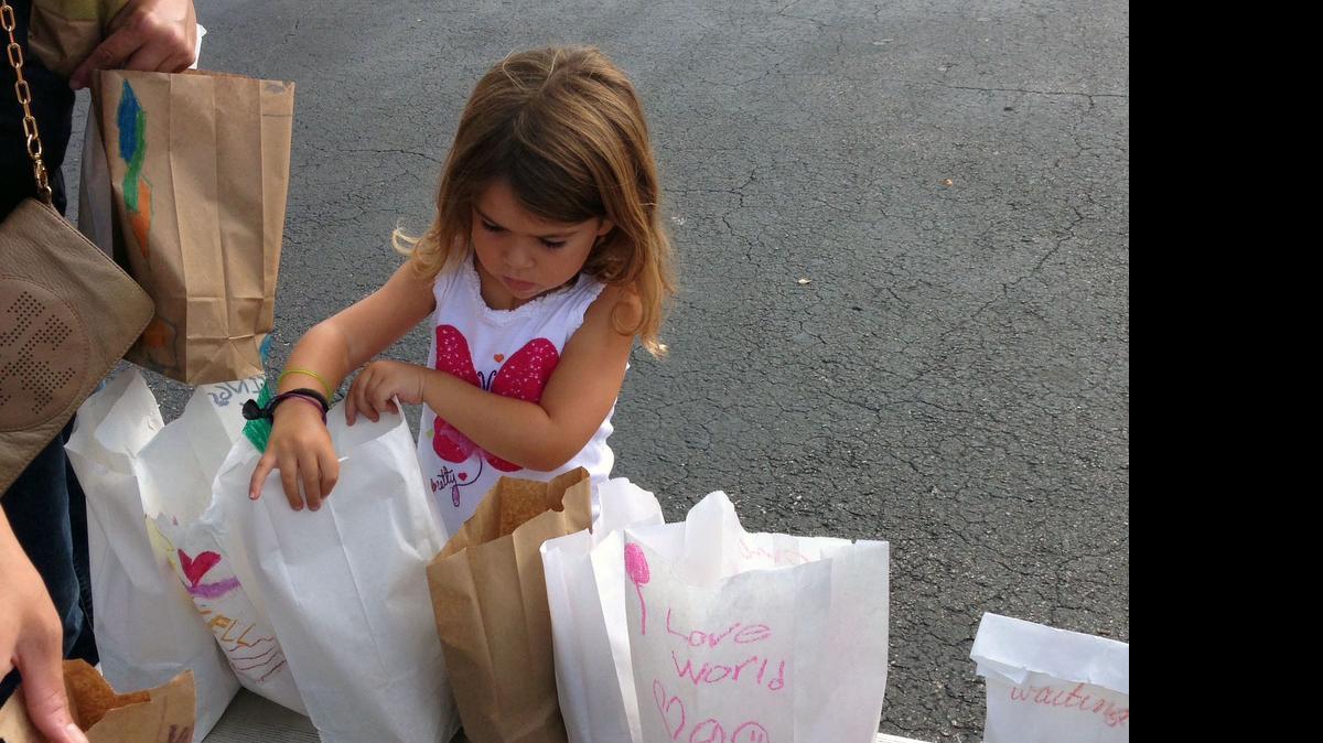 
Daniela Pérez, de 5 años, revisa que cada una de las bolsas de #teachHope70x7 contengan un sandwich, papitas y una golosina antes de meterlas en los vehículos de quienes luego las distribuirrán en las calles del downtown de Miami. 
