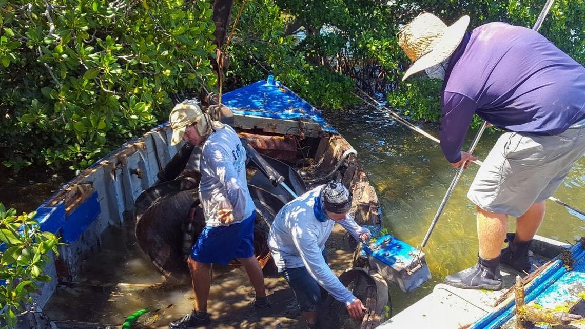 John Coffin (de izq. a der.) , David Coffin y Mike Schwing sacan una batería y otros materiales de una embarcación abandonada en las Marquesas.