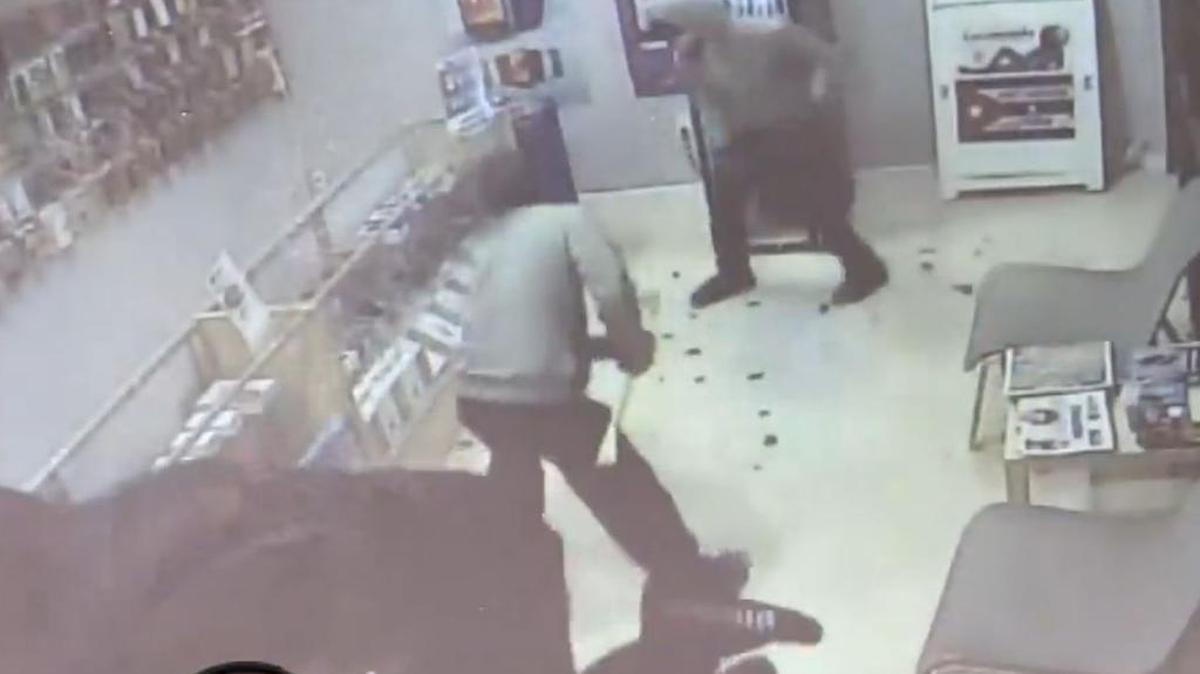 Captura del video de seguridad que muestra a los hombres destrozando la tienda de celulares.