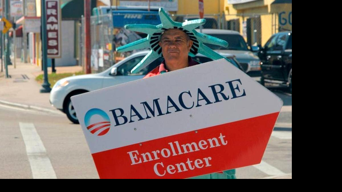
Un hombre disfrazado de la Estatua de la Libertad sostiene un anuncio para inscribirse al Obamacare en La Pequeña Habana.   
