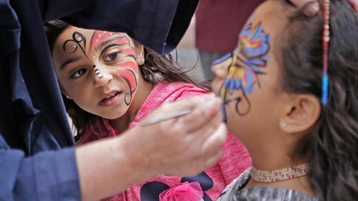 Un artista pinta la cara de Gabriela Silvia bajo la atenta mirada de Shanti, su hermanita.