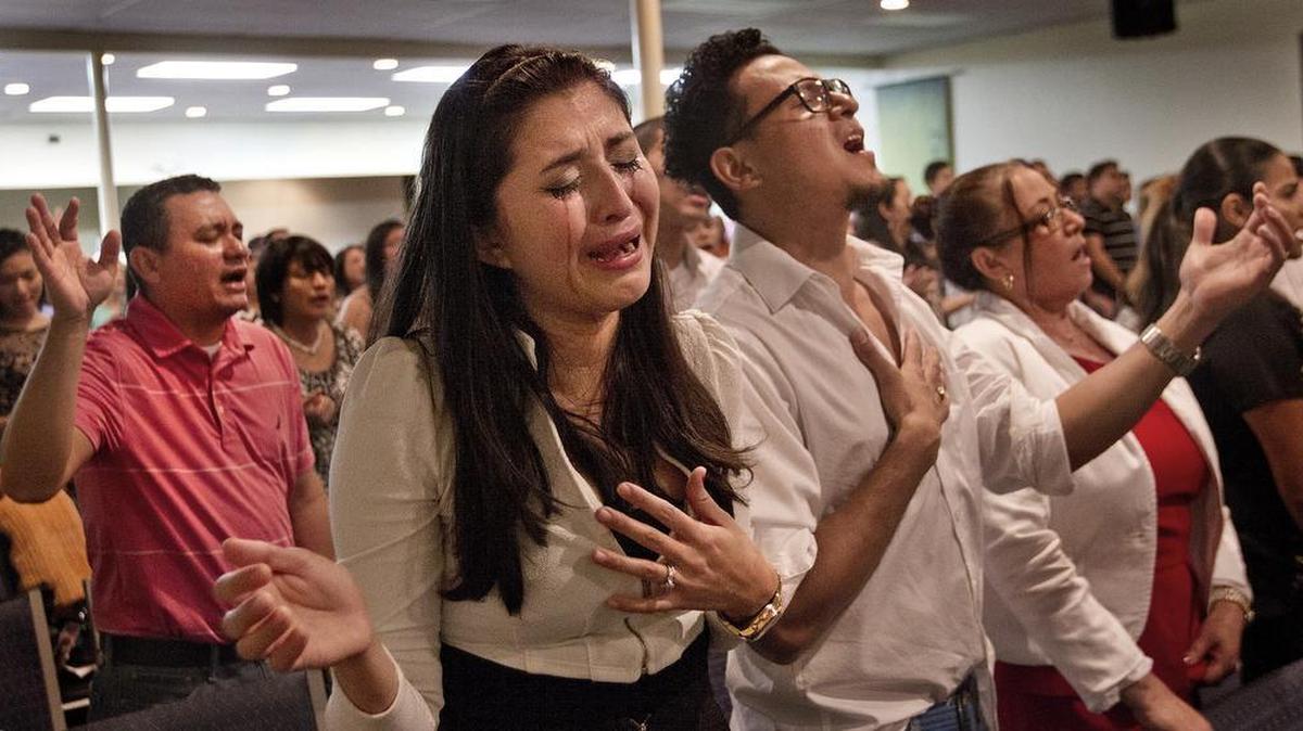 Los salvadoreños Elizabeth y su esposo Marvin reaccionan conmovidos durante un servicio religioso en la iglesia evangélica Amor Viviente, en North Lauderdale.